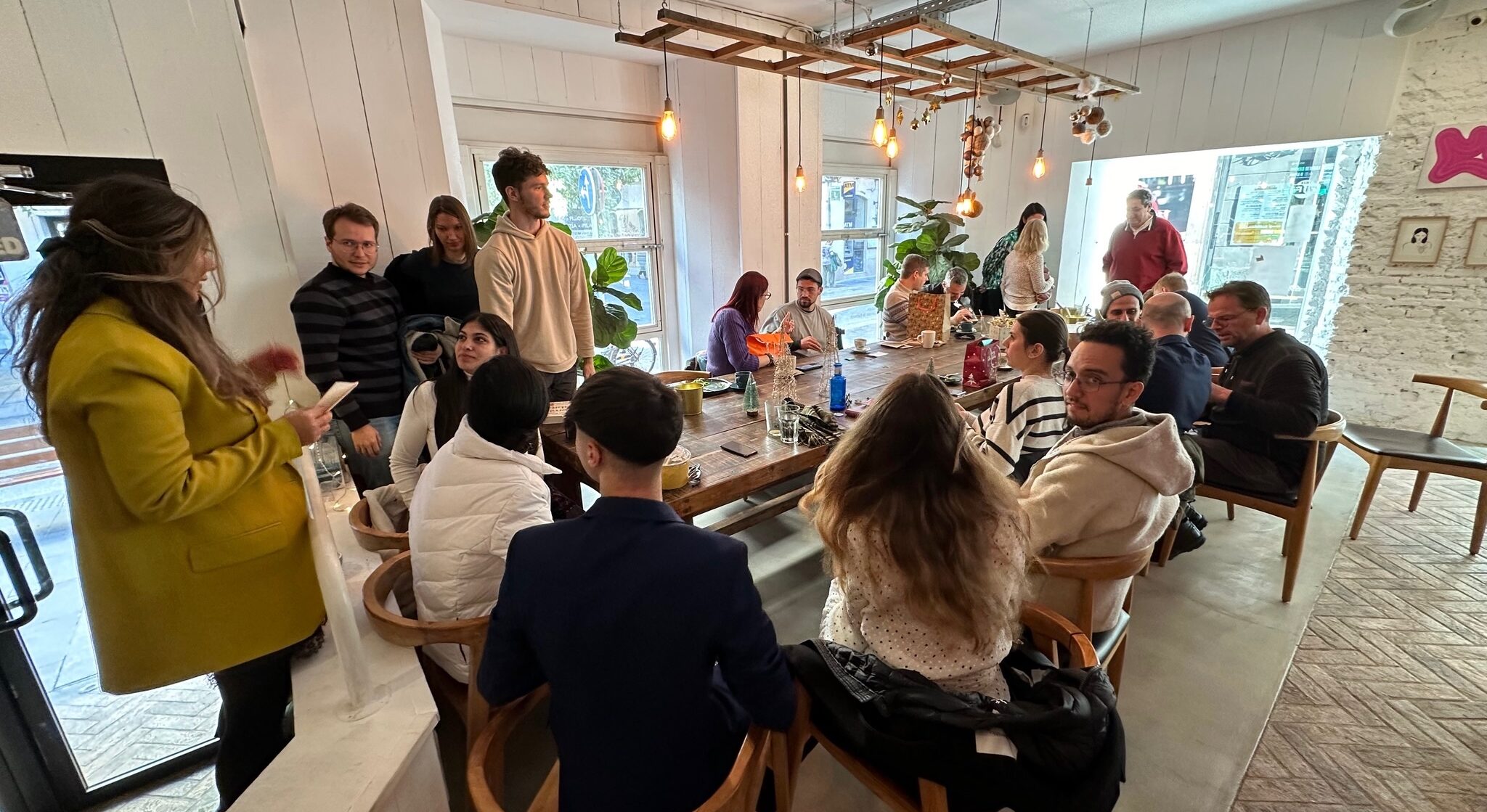 A group of diverse people sitting and standing while talking at a boho chic coffee shop.